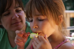 Jennifer watches Angelica savour a popsicle.
