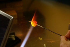 BJ melts the glass around the stick to make a bead.