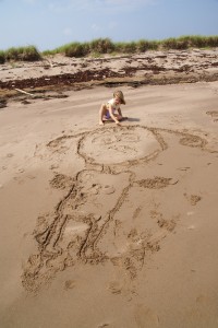 Morgane draws a princess-mermaid girl in the sand.