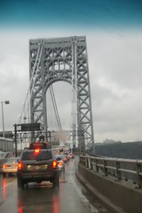 Over the bridge. It's a double-decker with cars driving on the lower part and trucks and cars on the top.